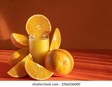 Fresh Orange Juice In Glass And Orange Slices.Orange Background.Monochromatic Food Photography.