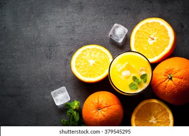 Fresh orange juice, orange slices, mint leaves and ice on dark background. Top view with copy space.