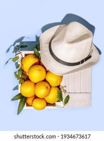 Fresh Oranges With Leaves In A Wooden Box And Summer Hat On A Blue Background. Healthy Season Foods. Natural Vitamin C. Eco Friendly Fruits Packaging. Farm, Local Fruits. Harvest Day Celebration