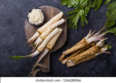 Fresh orgaanic horseradish or Horse-radish root on wooden cutting board.  top view