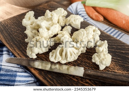 Fresh organic cauliflower cut into small pieces on cutting board.