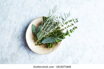 Fresh organic herbs in a ceramic bowl. Natural food ingredients. Marble background