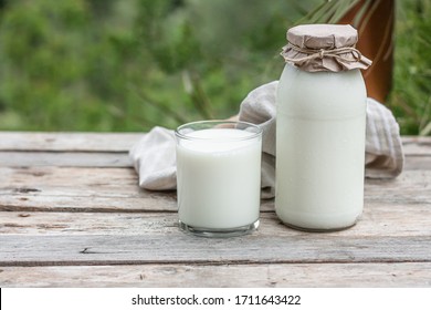 Fresh organic milk in glass and bottle on rustic wooden table on nature background. Vegetable milk, vegan milk, Kefir, or Turkish Ayran drink for helthy eating. Space for text