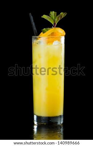 fresh organic orange juice and vodka in a tall glass isolated on a black background garnished with fresh green mint