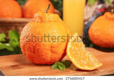 Fresh organic orange with thick bumpy skin and sweet juicy flesh on wooden cutting board with mint garnish in rustic kitchen setting