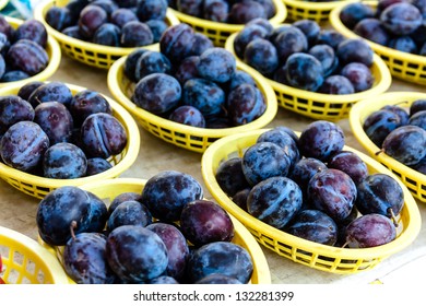 Fresh organic plums in yellow plastic baskets on display at local farmers market - Shutterstock ID 132281399