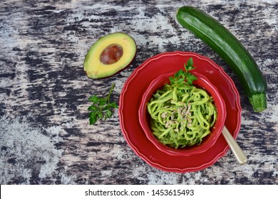 Fresh Organic Raw Zucchini Noodles Or Zoodles With Avocado Pesto Sauce Garnish With Parsley And Sunflower Seeds. 