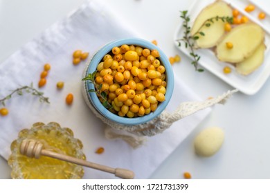 Fresh organic sea buckthorn berries in blue clay pot with honey, ginger and thyme. Tea preparation. flat lay top view - Shutterstock ID 1721731399