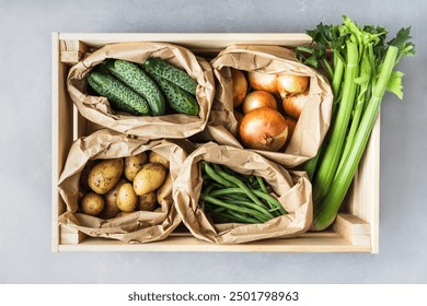 Fresh organic vegetables in a wooden box. Crate with celery, onions, potatoes, cucumbers and green beans. Top view - Powered by Shutterstock