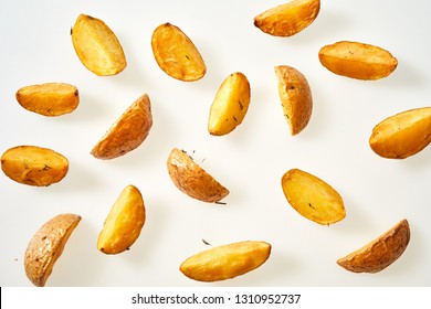 Fresh Oven Baked Potato Wedges With Their Skins Seasoned With Rosemary Scattered On A White Background Viewed From Overhead