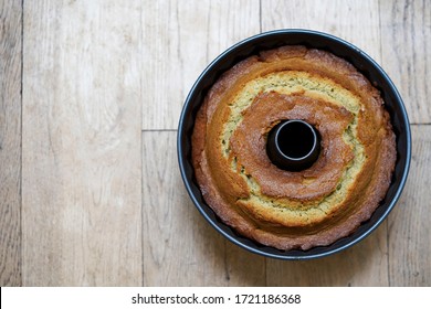 Fresh from the oven bundt cake in the tin, on the wooden background