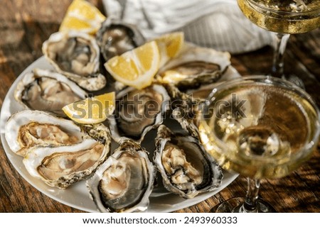 Fresh Oysters with champagne close up top view, over wood background, open french Fine de Claire oysters. Dinner in a restaurant, sea food. Served table with Oyster. Gourmet food, delicatessen. 