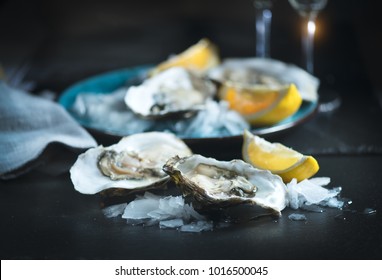 Fresh Oysters close-up on blue plate, served table with oysters, lemon and ice. Healthy sea food. Oyster dinner with champagne in restaurant. Gourmet food.