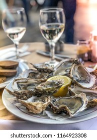 Fresh oysters served on a table in summer restaurant with a glass of white wine, lemon and a bread