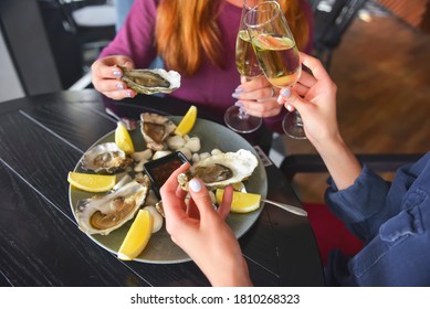 Fresh Oysters As Well As Fine Dining, Two Young Attractive Woman Eating Oysters In Restaurant And Drinking Champagne. Eating Out Concept, Dinner In Restaurant.