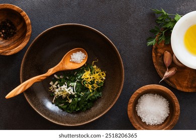 Fresh parsley, lemon, garlic, olive oil in ceramic bowl over dark background, gremolata ingredients, high angle view - Powered by Shutterstock