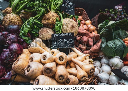 Fresh parsnip vegetables in the basket ready for sale at a fruit and veg stall on display at Borough Market in London