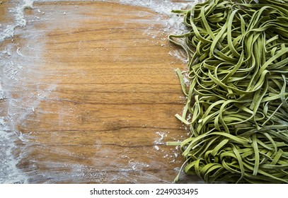 Fresh pasta. Homemade italian raw fettuccine pasta with spinach on wooden table background - Powered by Shutterstock