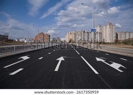 Fresh pavement on a new road. Traffic marking, learning to drive in the city. high-rise buildings in the background.