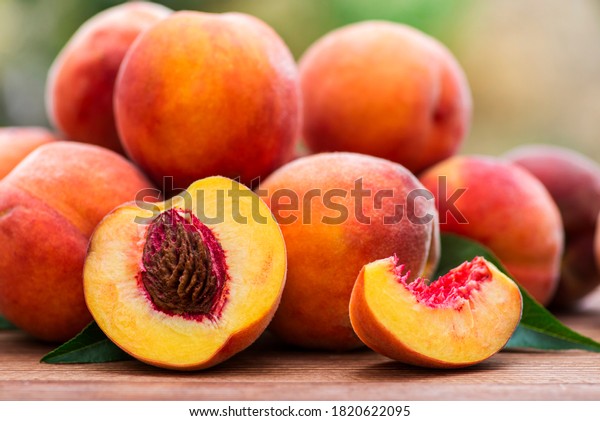 Fresh peaches on wooden table. Ripe peaches with\
leaves on a wooden board.