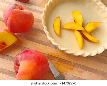 Fresh Peaches, Whole And Sliced, With Raw Pie Crust On Cutting Board