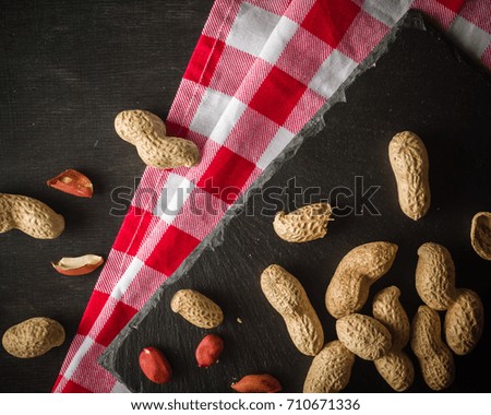 Fresh peanuts in peel and shell. Dark wooden background. Vegetarian food