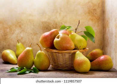 fresh pears with leaves in a basket on wooden table