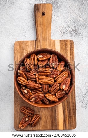 Fresh pecan nuts arranged in a rustic wooden bowl over a plain white backdrop giving a clean organic look suitable for food ingredient and nutrition content.