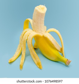 Fresh peeled bitten banana on blue background