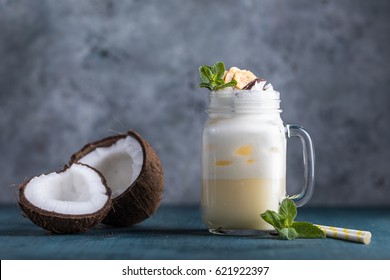 Fresh pina colada cocktail with coconut milk and banana on the blue wooden background