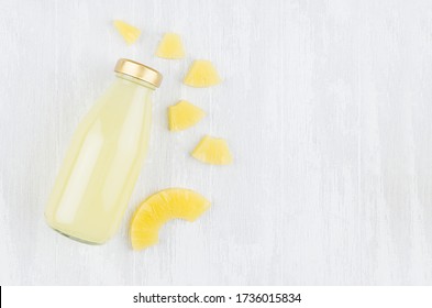 Fresh Pinapple Yellow Juice In Glass Bottle With Sliced Fruit On White Wood Board, Top View, Copy Space, Mock Up For Design, Advertising, Branding Identity.