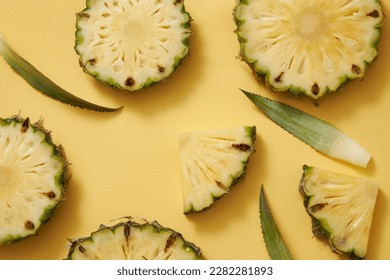 Fresh pineapple (Ananas comosus) slices, circles and triangles, green leaves decorated on yellow background. Advertising photo, pineapple is rich in vitamin C brings unexpected benefits to the skin.