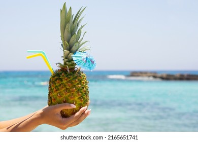 Fresh Pineapple  drink coctail on woman hand at tropical beach and sea background with copy space . Tropical summer concept  card.