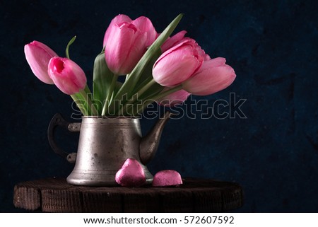 Fresh pink tulip flowers bouquet in old teapot with chocolate heart. View with copy space Spring holiday concept
