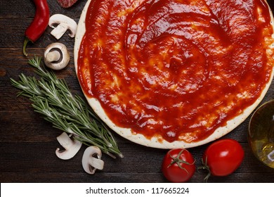 Fresh Pizza Dough With Tomato Sauce And Natural Ingredients For Cooking On Wooden Table