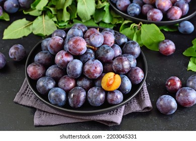 Fresh plums on plate over dark stone background - Powered by Shutterstock