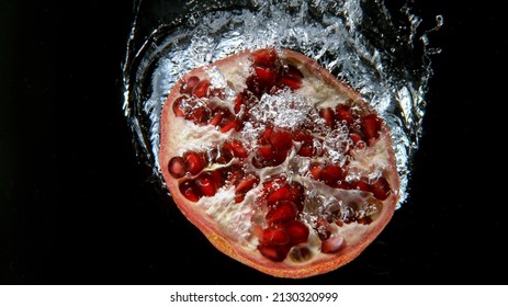 Fresh Pomegranate Falling Into Water, Freeze Motion, Underwater View.