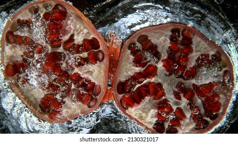 Fresh Pomegranate Falling Into Water, Freeze Motion, Underwater View.