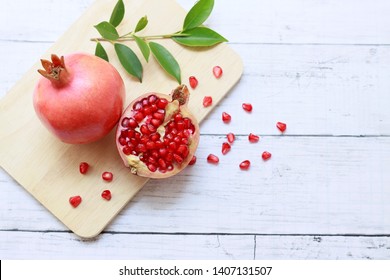 Fresh pomegranate fruit with half pomegranate and seeds on wooden plate, Top view, Copy space