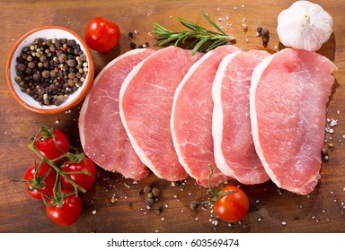 fresh pork with ingredients for cooking on wooden board