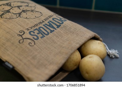 Fresh Potatoes In A Brown Sack On Grey Kitchen Bench. Top View