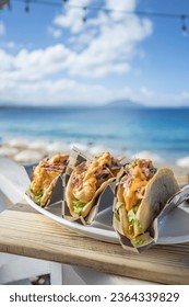 The fresh prepared tacos on the wooden board on the background of the beach
