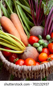 Fresh Produce From A Vegetable Garden Gathered In A Rustic Wicker Basket - Carrots, Beetroot, Beans, Cucamelons And Red Tomatoes