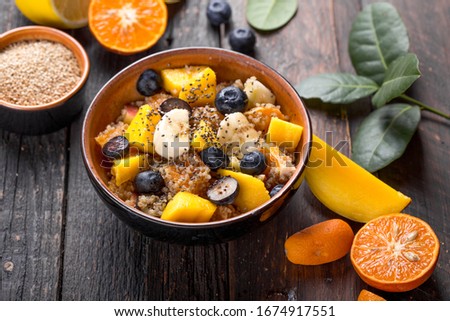 Fresh quinoa organic fruit salad in bowl on wooden  background. Helthy superfood detox concept.  Vegan/vegetarian food. Space for text. Top view
