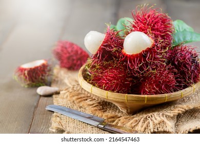 Fresh Rambutan fruits with leaves on bamboo basket on wood background. fruit Southeast Asia,