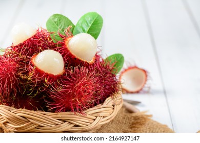 Fresh Rambutan fruits with leaves on bamboo basket on wood background. fruit Southeast Asia