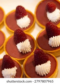 Fresh raspberry tarts are a bite size baked good presented in multiples as a creamy dessert or snack choice 