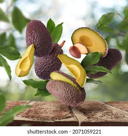 Fresh Raw Avocados Falling In The Air On Wooden Table Over Defocused Bokeh Background. Food Levitation Concept. Zero Gravity Fruit Conception. High Resolution Image