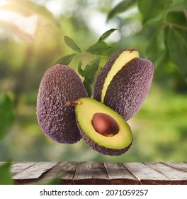 Fresh Raw Avocados Falling In The Air On Wooden Table Over Defocused Bokeh Background. Food Levitation Concept. Zero Gravity Fruit Conception. High Resolution Image