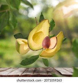 Fresh Raw Avocados Falling In The Air On Wooden Table Over Defocused Bokeh Background. Food Levitation Concept. Zero Gravity Fruit Conception. High Resolution Image